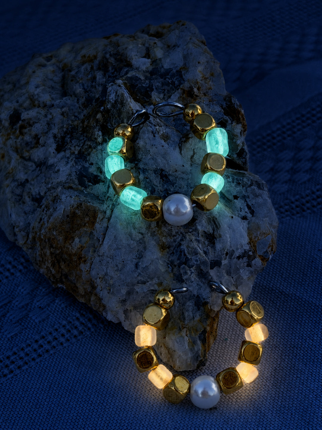 After Hours Ring glowing teal and gold in the dark on rock