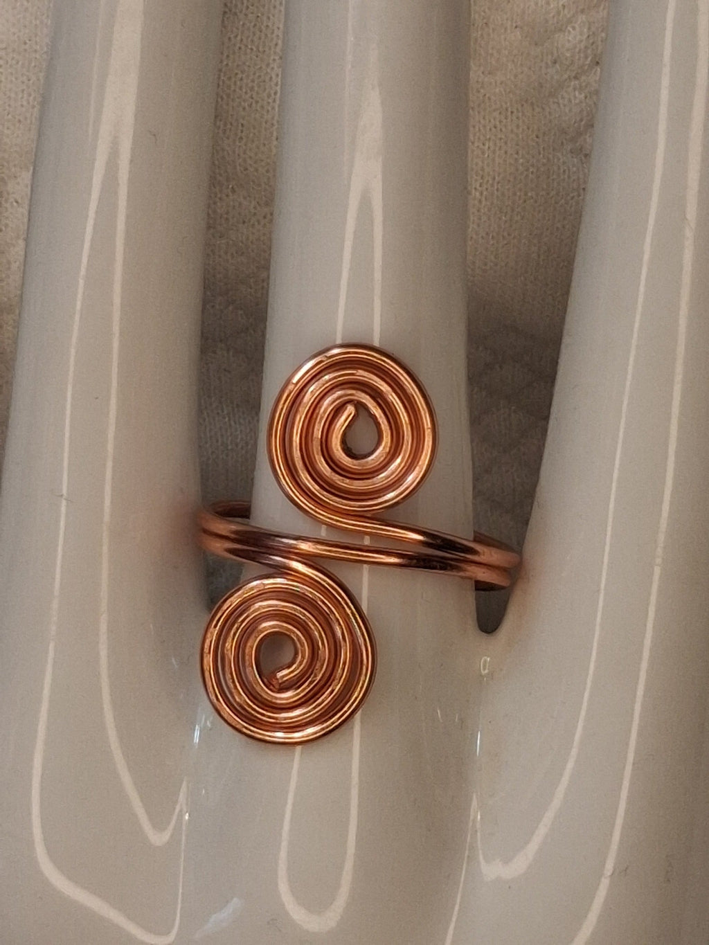 Copper adjustable wire ring 5 with two round spirals and a diagonal wrapped band on a white jewelry display.