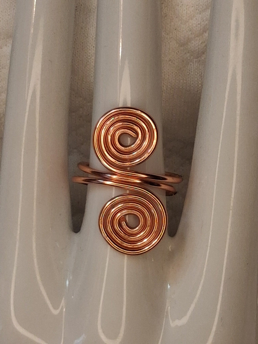 Copper adjustable wire ring 9 with two round spiral ends and a wrapped band on a white jewelry display.