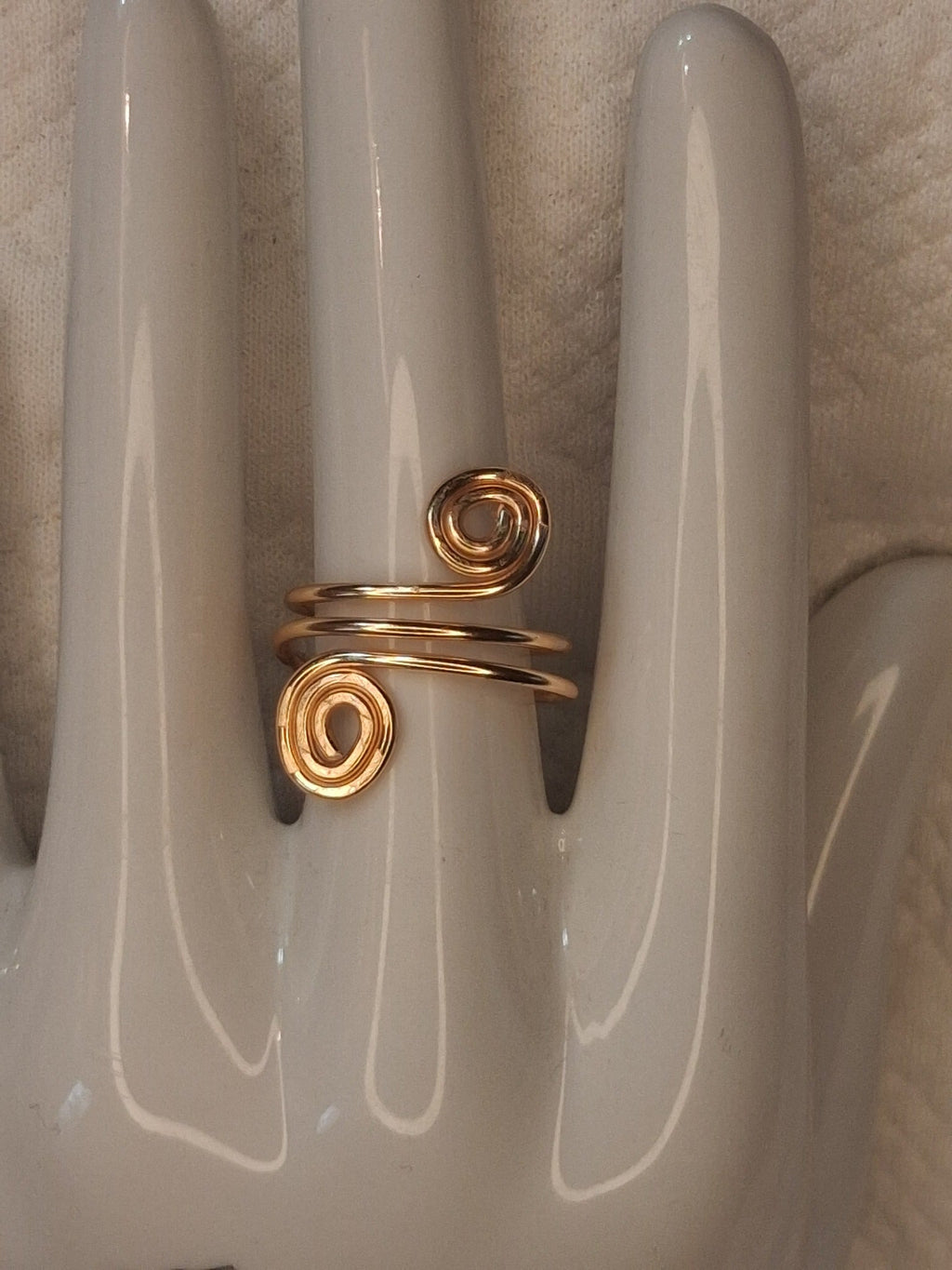 Gold 1 adjustable wire ring with two round spiral ends separated by a wide wrapped band, displayed on a white ceramic jewelry hand.