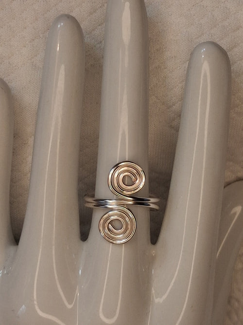 Silver adjustable wire ring 1 with two round spiral ends on a white jewelry display.