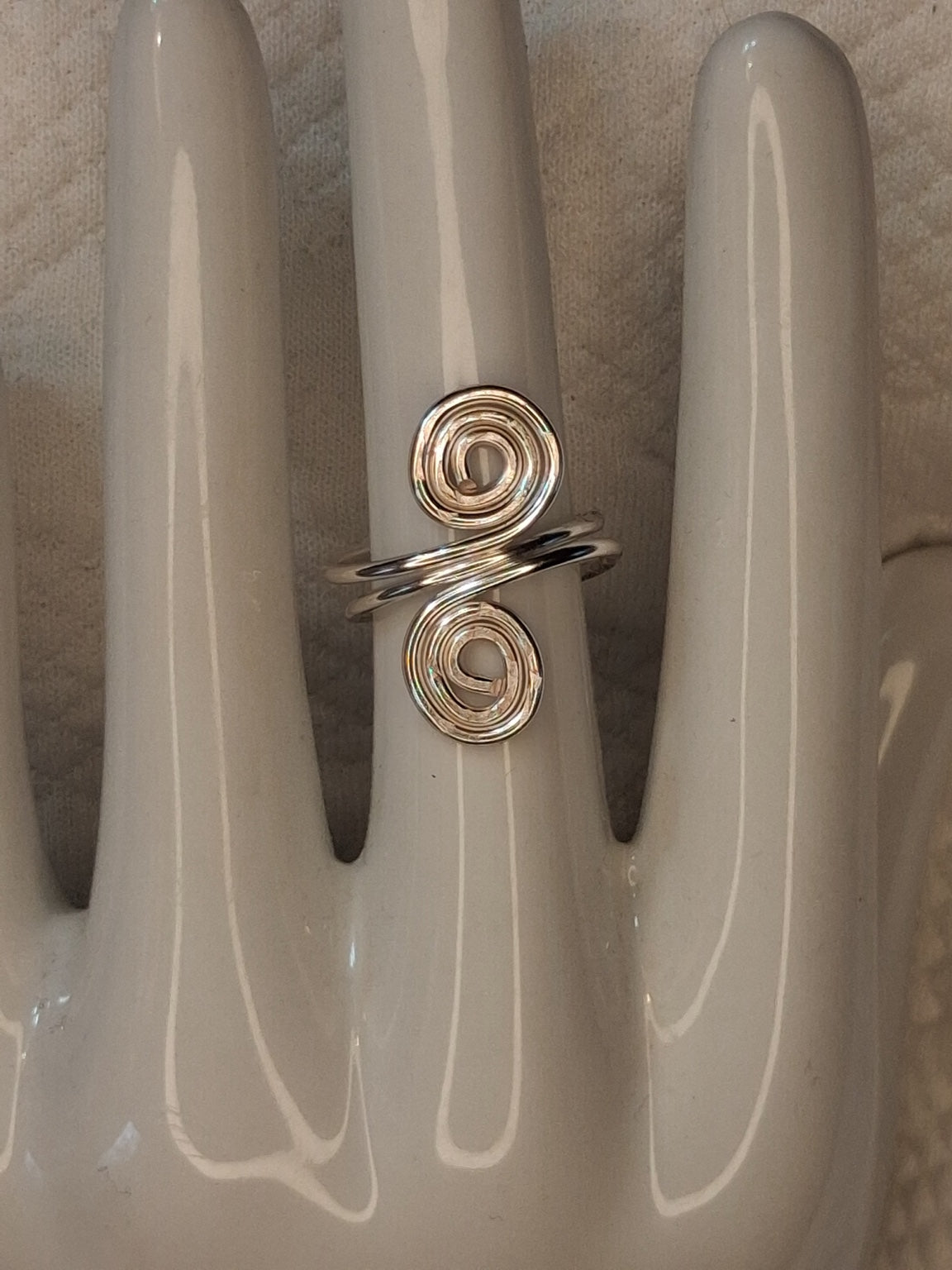 Silver adjustable wire ring 2 with two irregular spiral ends on a white jewelry display.