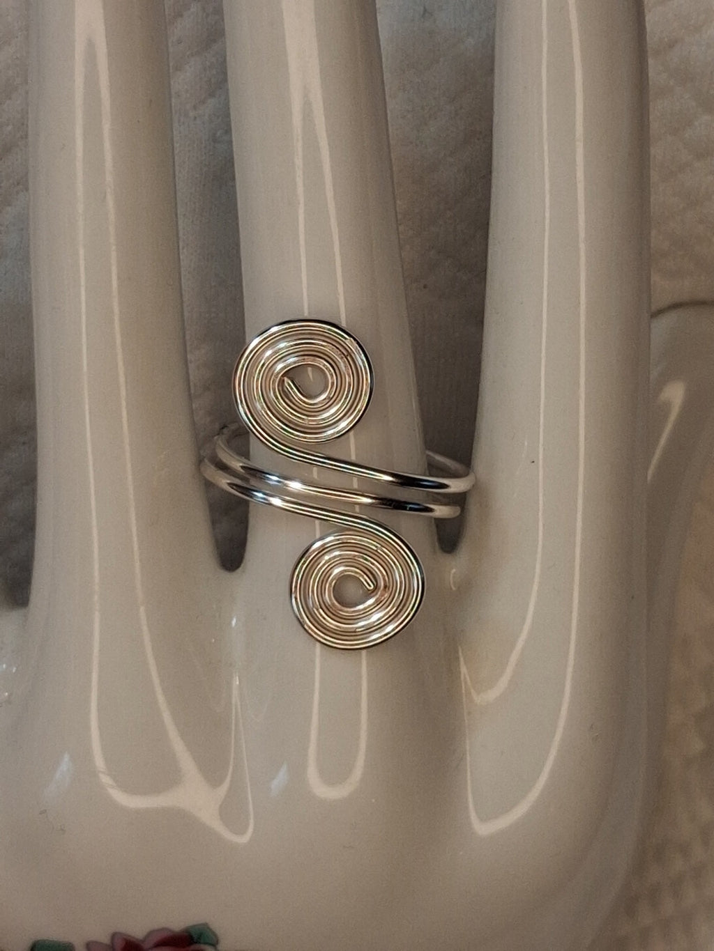 Silver adjustable wire ring 6 with two round spirals and an angled wrapped band on a white jewelry display.