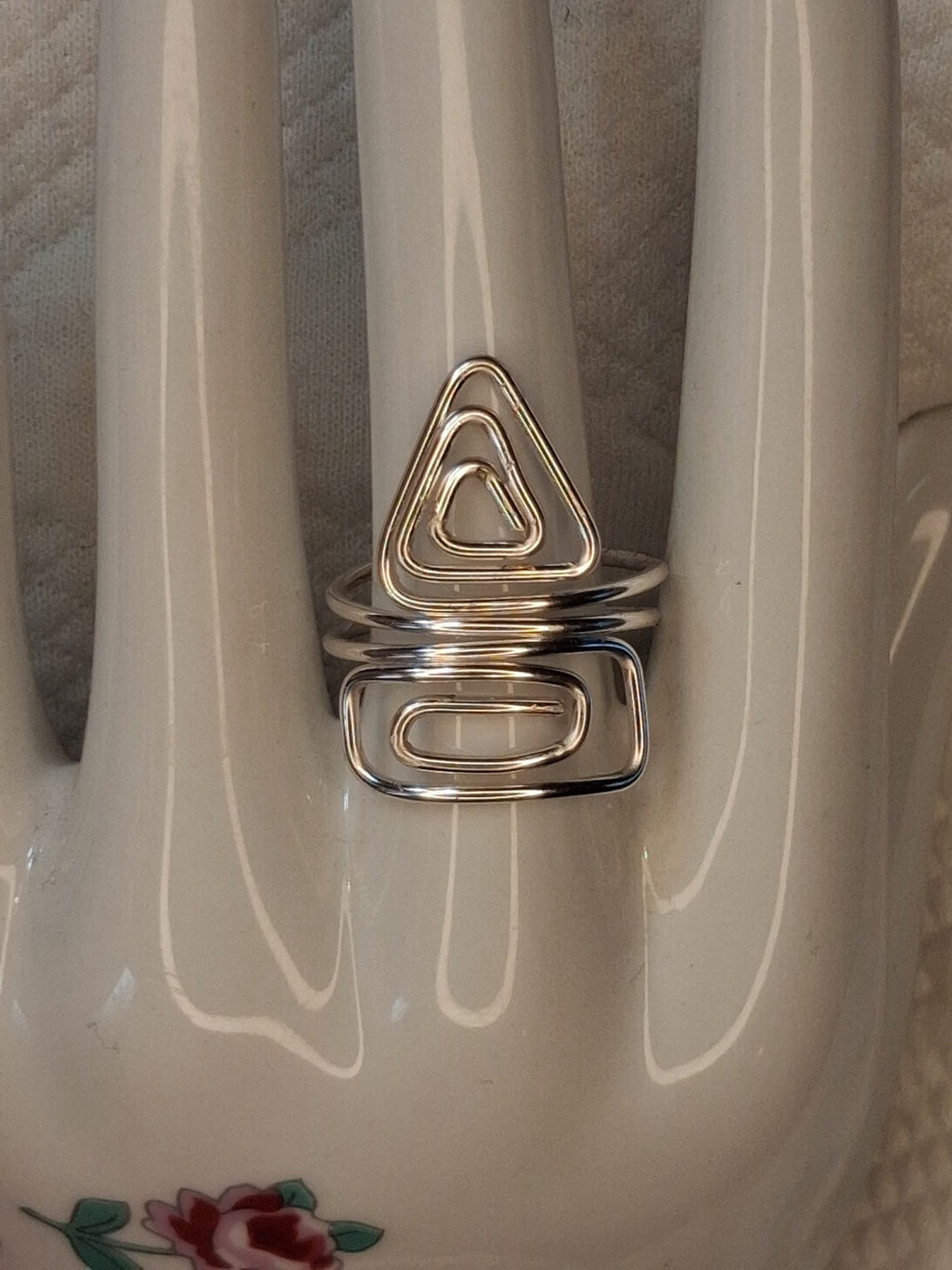 Silver adjustable wire ring 8 with a triangular spiral and an elongated rectangular spiral on a white jewelry display.