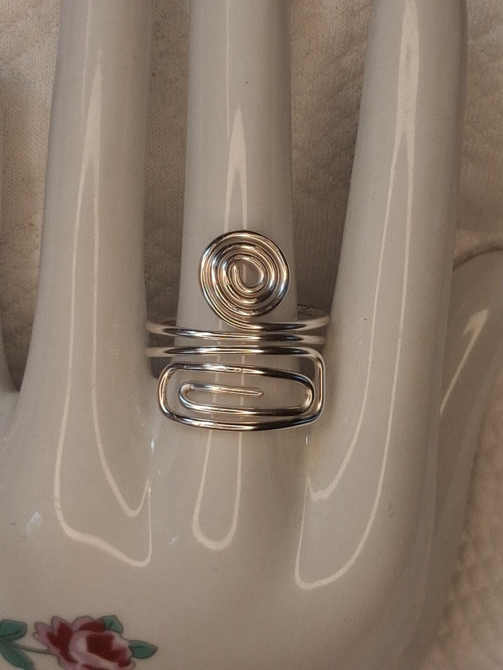 Silver adjustable wire ring 9 with a round spiral and an elongated rectangular spiral on a white jewelry display.